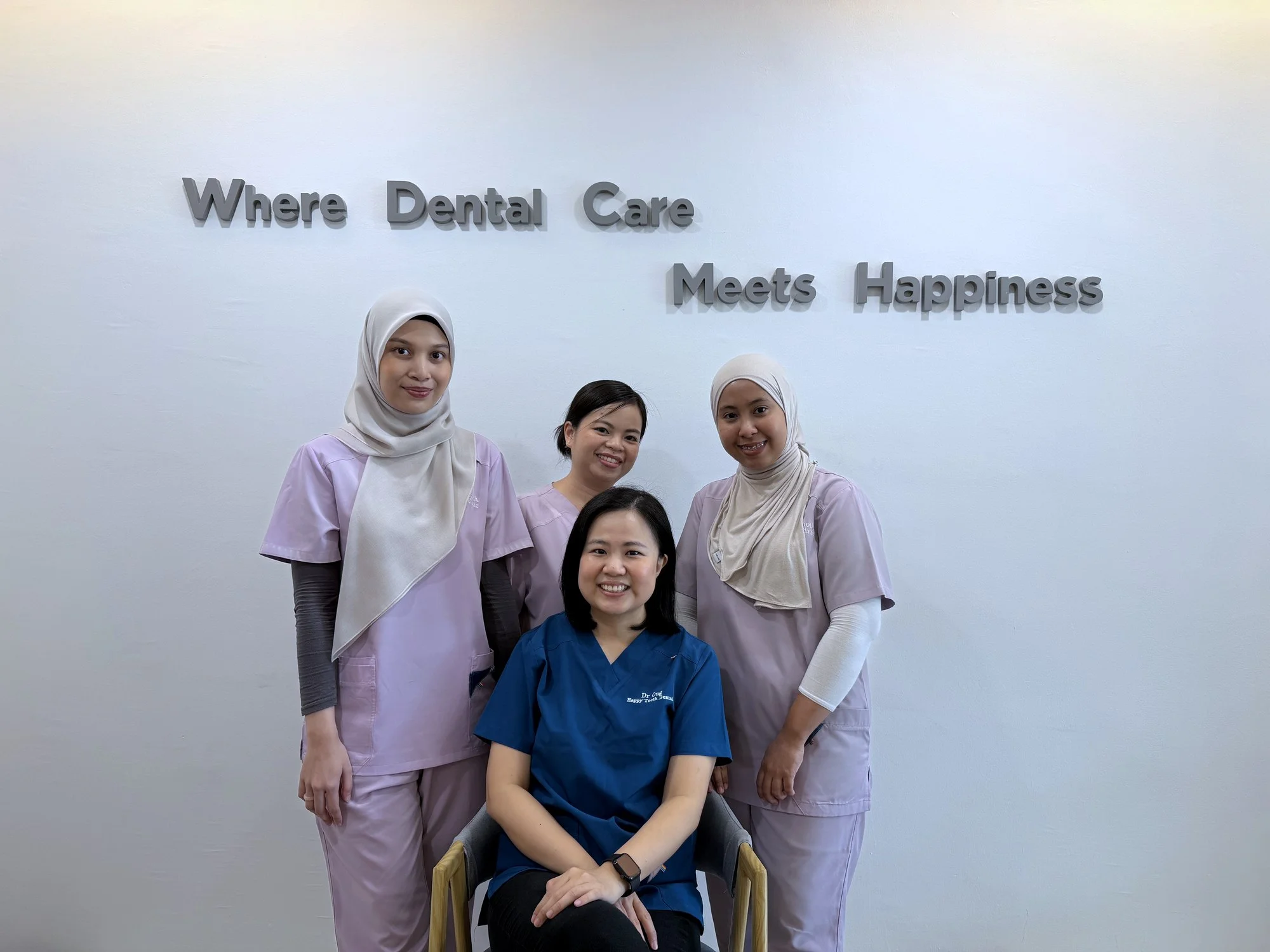 Dr. Ong and the Happy Tooth team in front of the “Where Dental Care Meets Happiness” wall